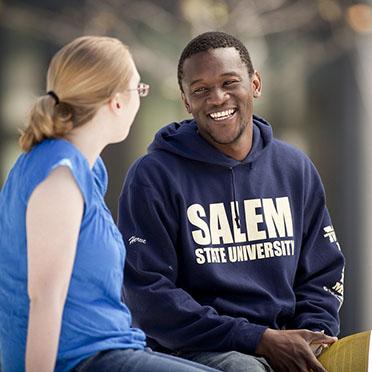 Two Salem State students outside discussing a book
